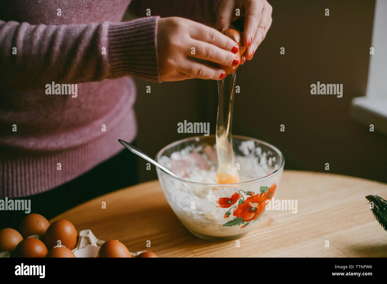 https://c8.alamy.com/comp/TTNFW6/midsection-of-woman-breaking-egg-in-bowl-on-wooden-table-at-home-TTNFW6.jpg