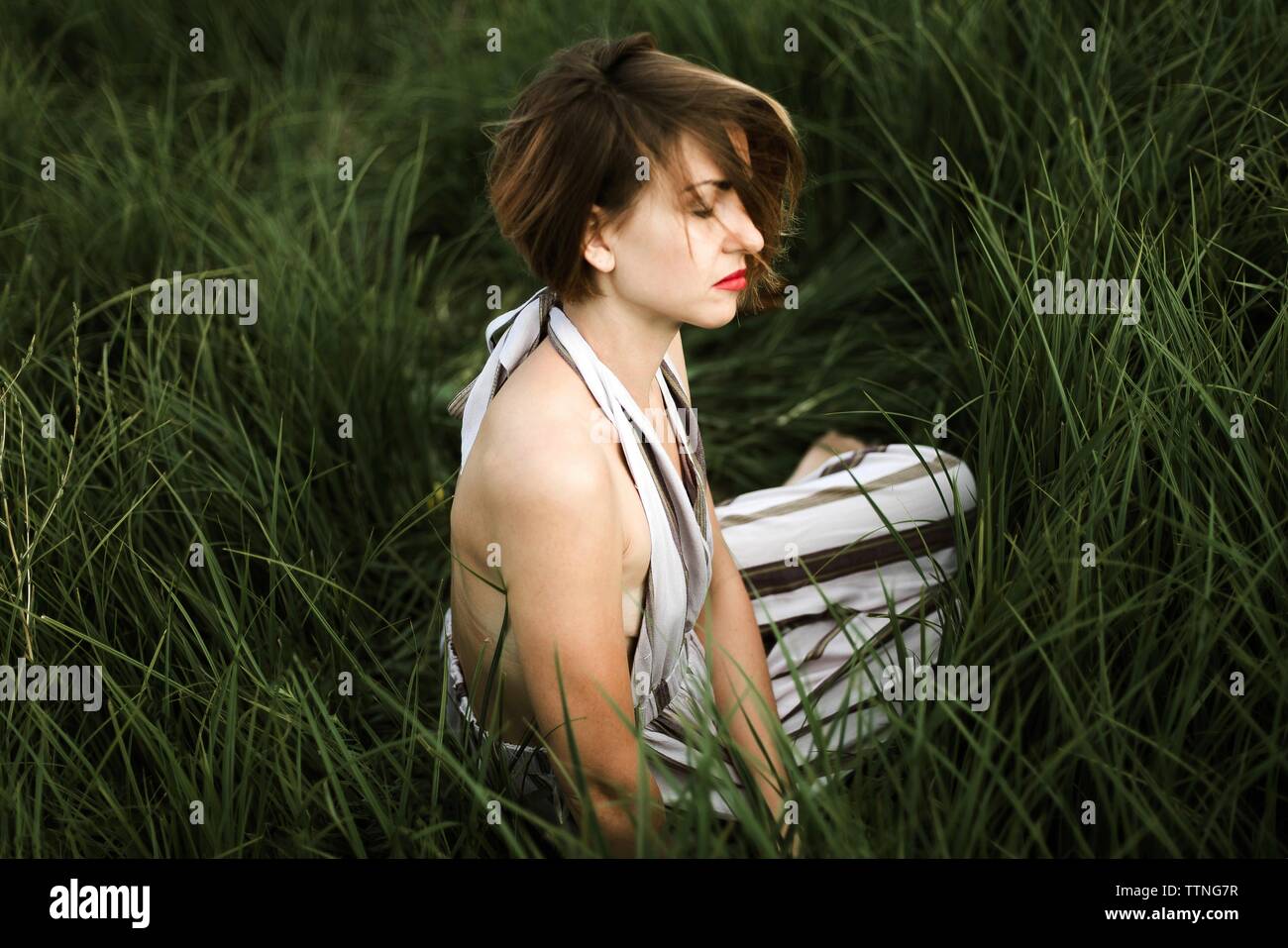 Portrait of beautiful woman in dress relaxing on grassy field Stock Photo