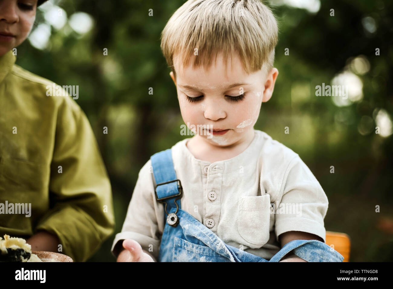 Portrait of boy preparing food with brother in yard Stock Photo