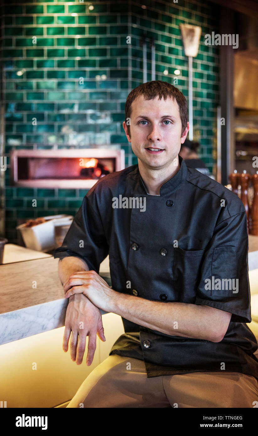Portrait of confident chef sitting in commercial kitchen Stock Photo