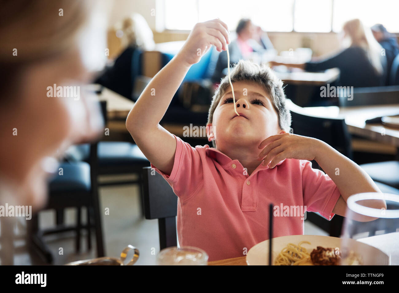 Cute boy eating noodle at restaurant table Stock Photo