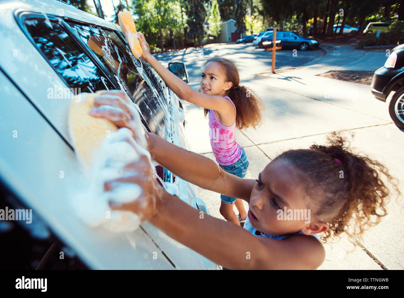High angle view of girls washing car in driveway Stock Photo