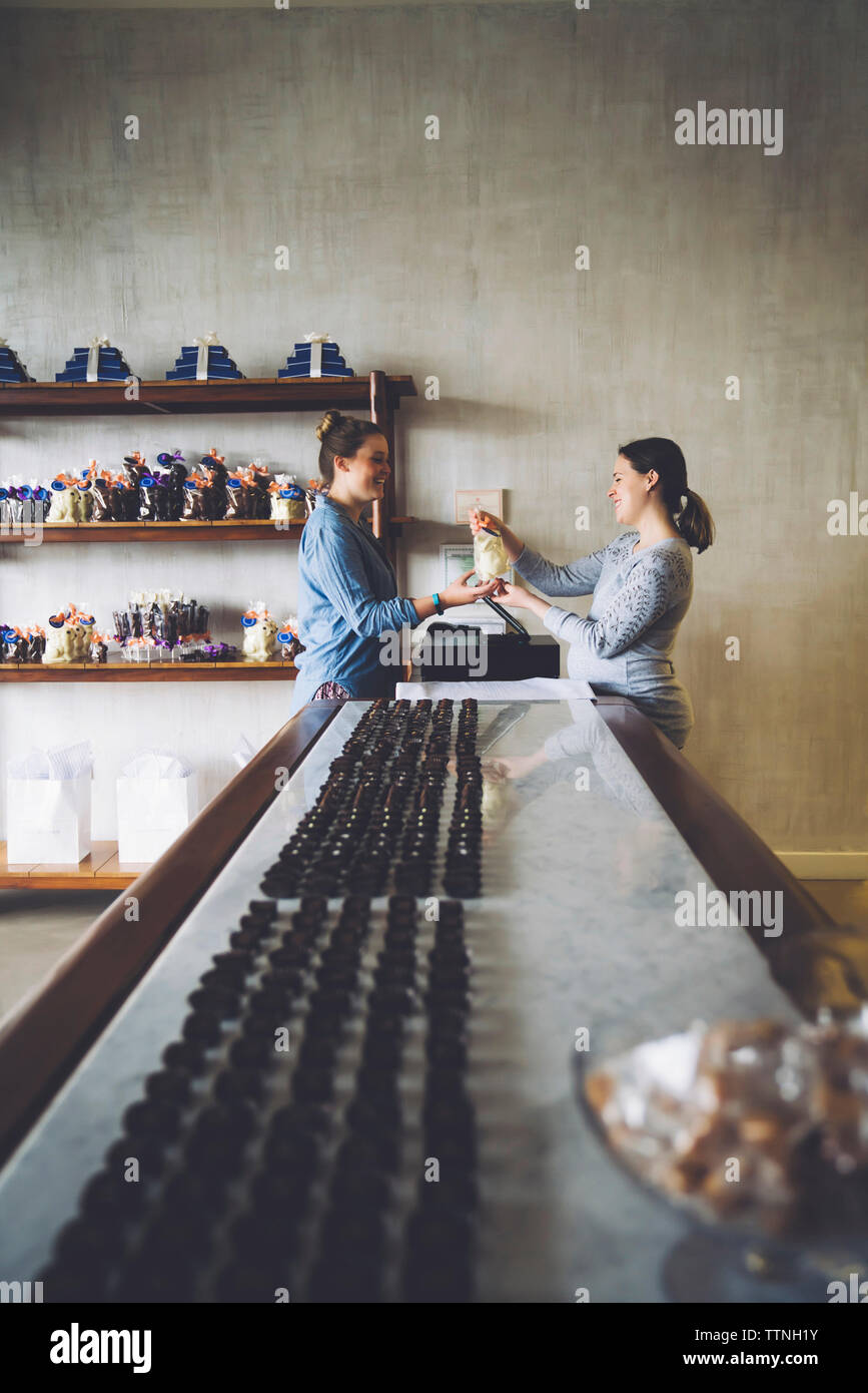 Side view of owner selling sweet food to female customer at bar counter in store Stock Photo Alamy