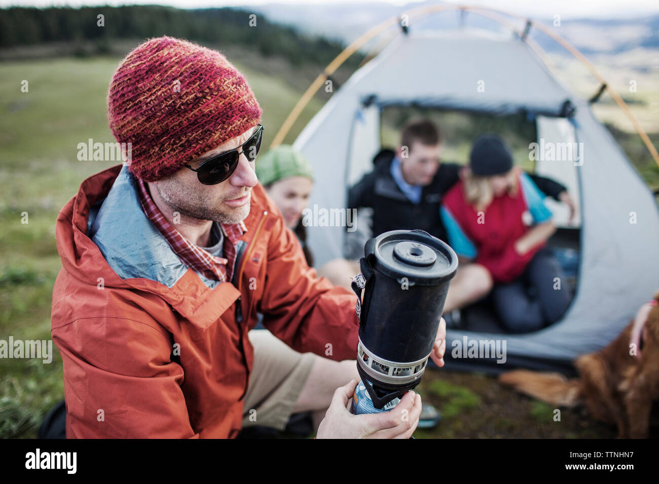 Man warming drink with friends in background Stock Photo