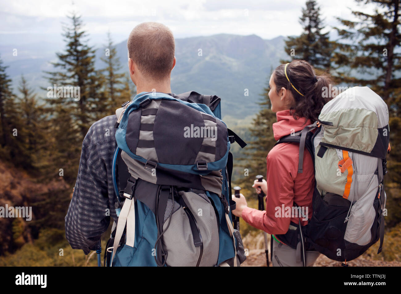 Hikers carrying backpacks while looking at mountains Stock Photo