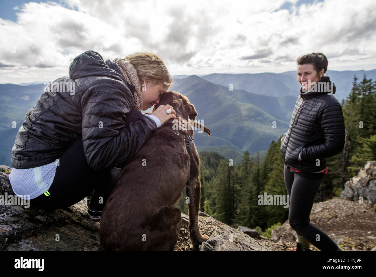 Women enjoying with dog at mountain cliff during hiking Stock Photo