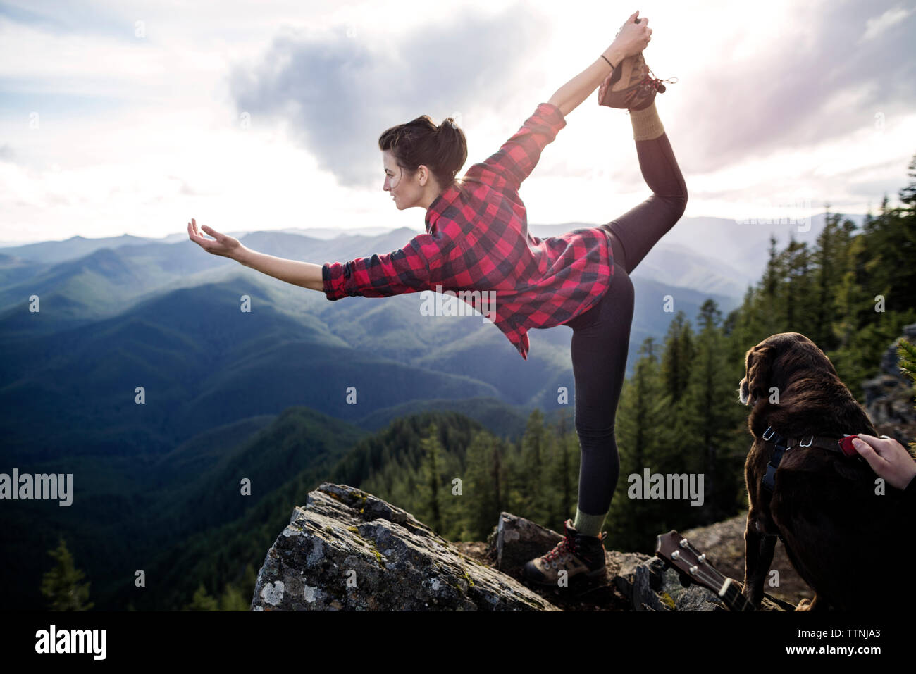 Woman standing on one leg at mountain cliff Stock Photo