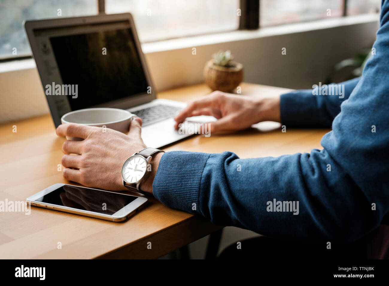 Cropped image of man using laptop on table in cafe Stock Photo