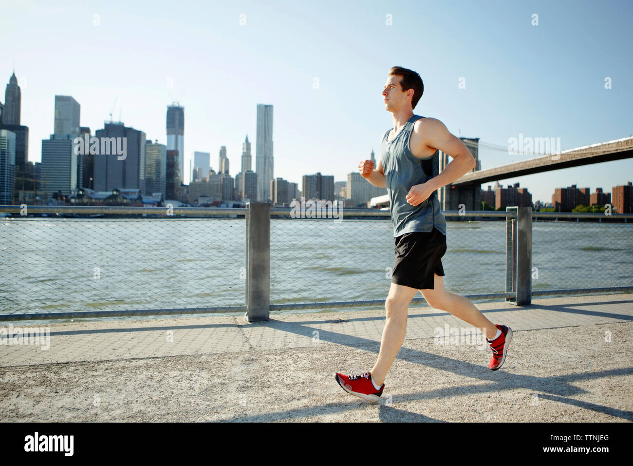 Side view of man jogging on pathway by East River against sky Stock Photo -  Alamy