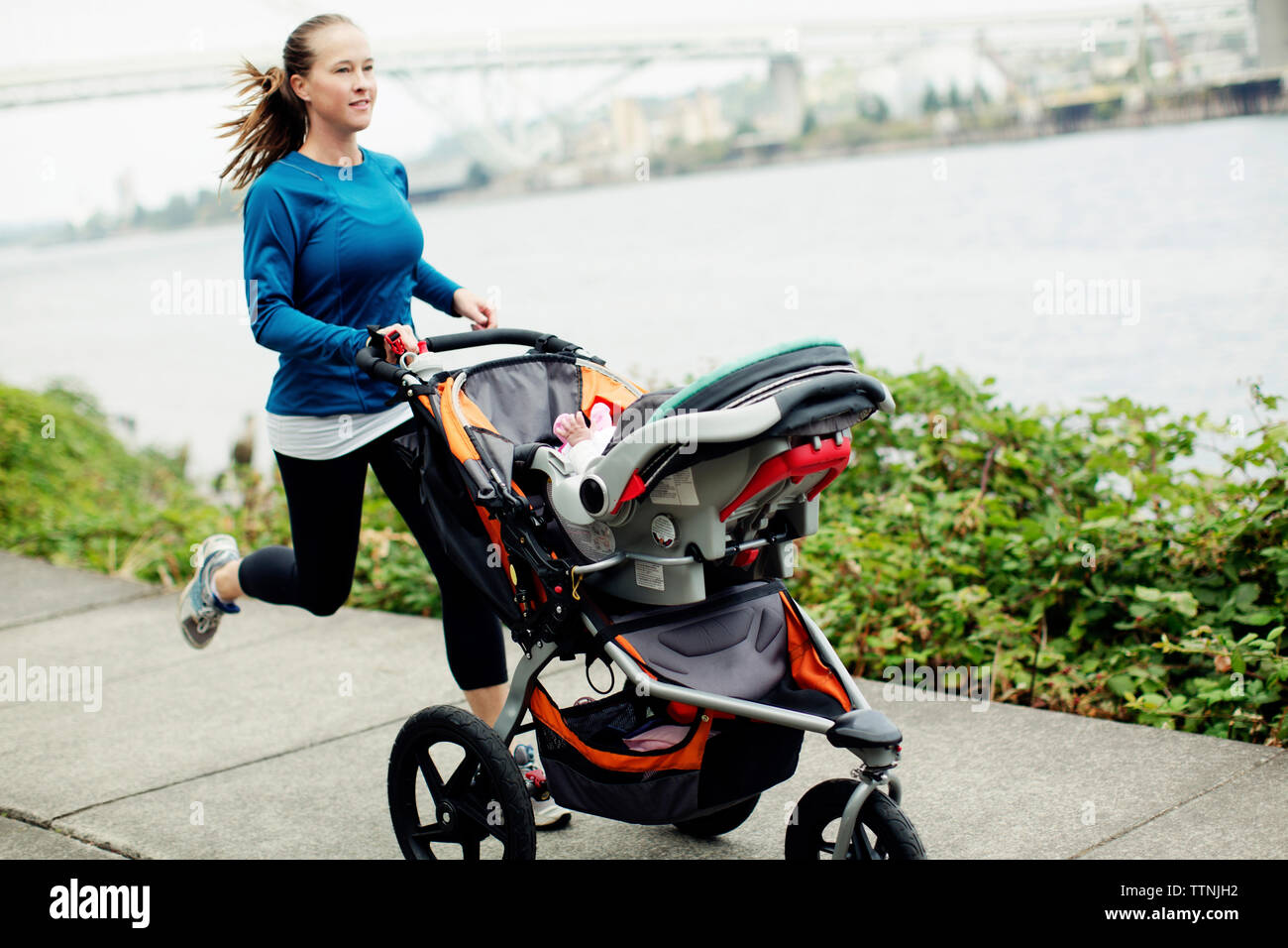 Syndicate Lige forskel Woman running with baby stroller on footpath by river in city Stock Photo -  Alamy