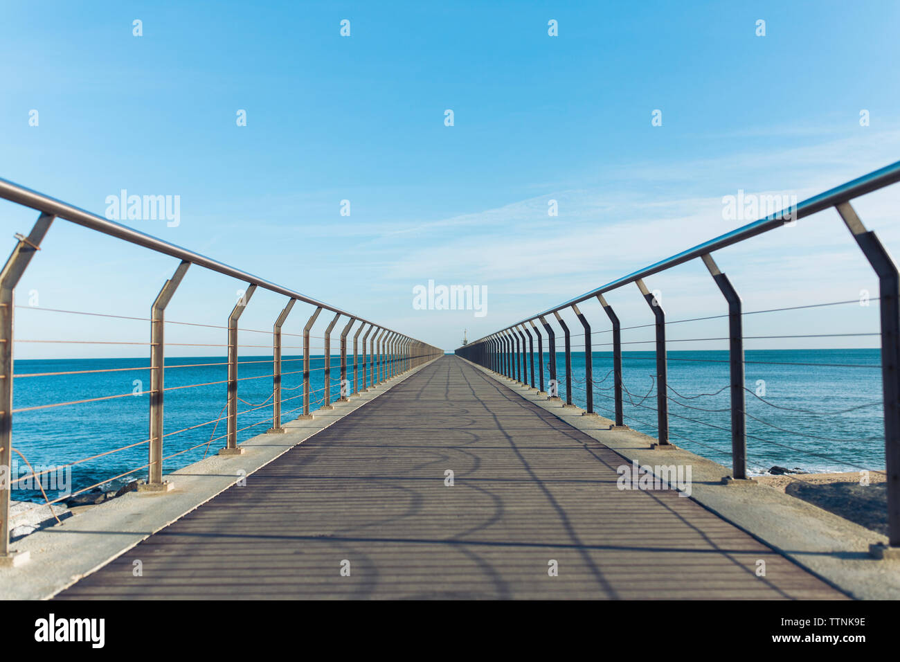 Diminishing perspective of pier over sea against sky Stock Photo