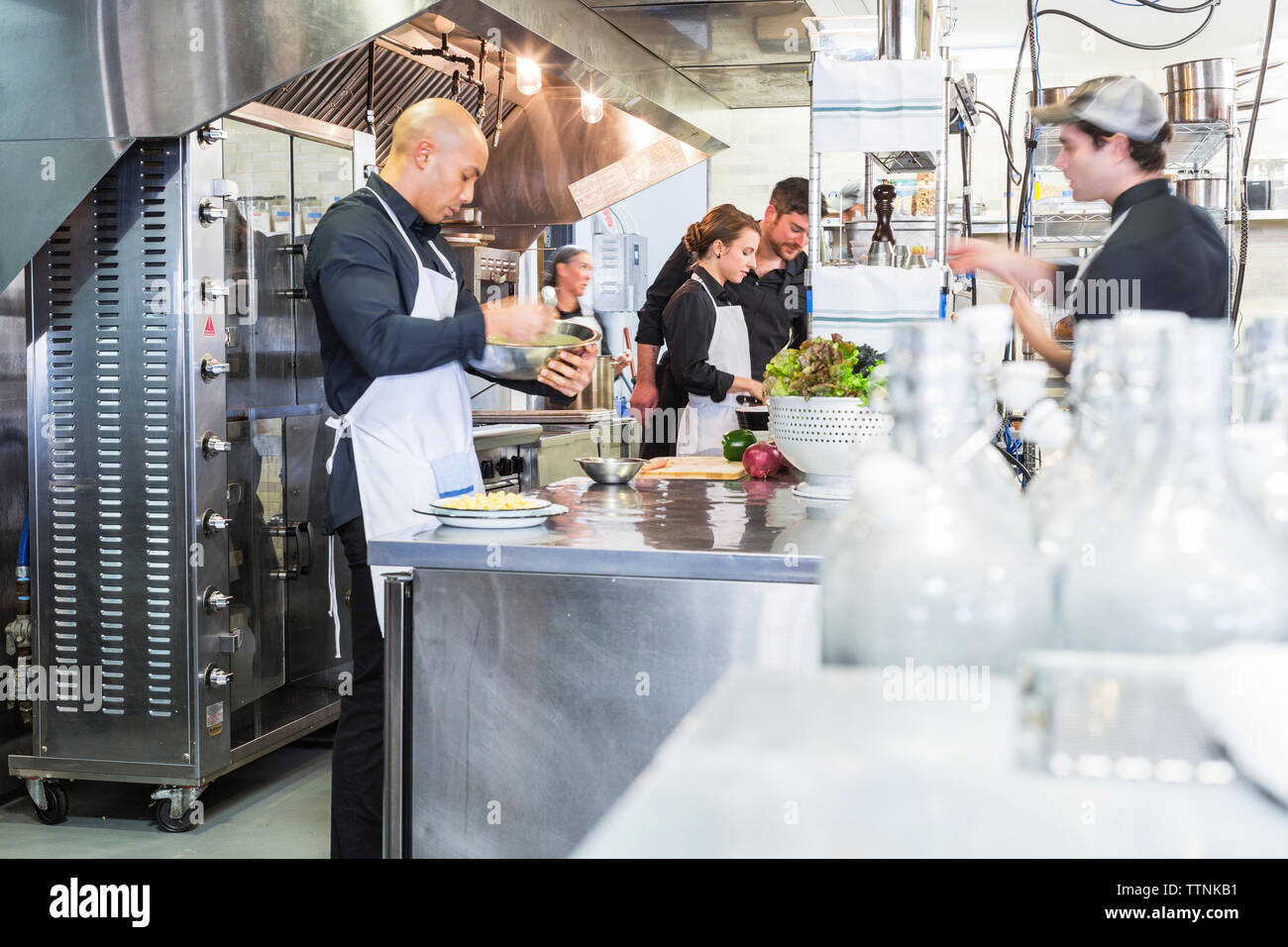 Chefs preparing food in commercial kitchen at restaurant Stock Photo