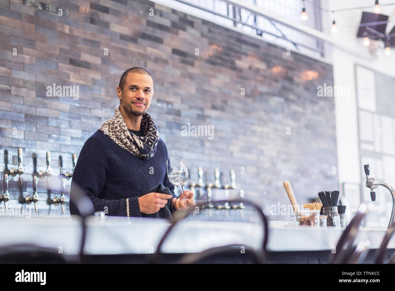 Bartender looking away while holding wineglass at bar counter in restaurant Stock Photo