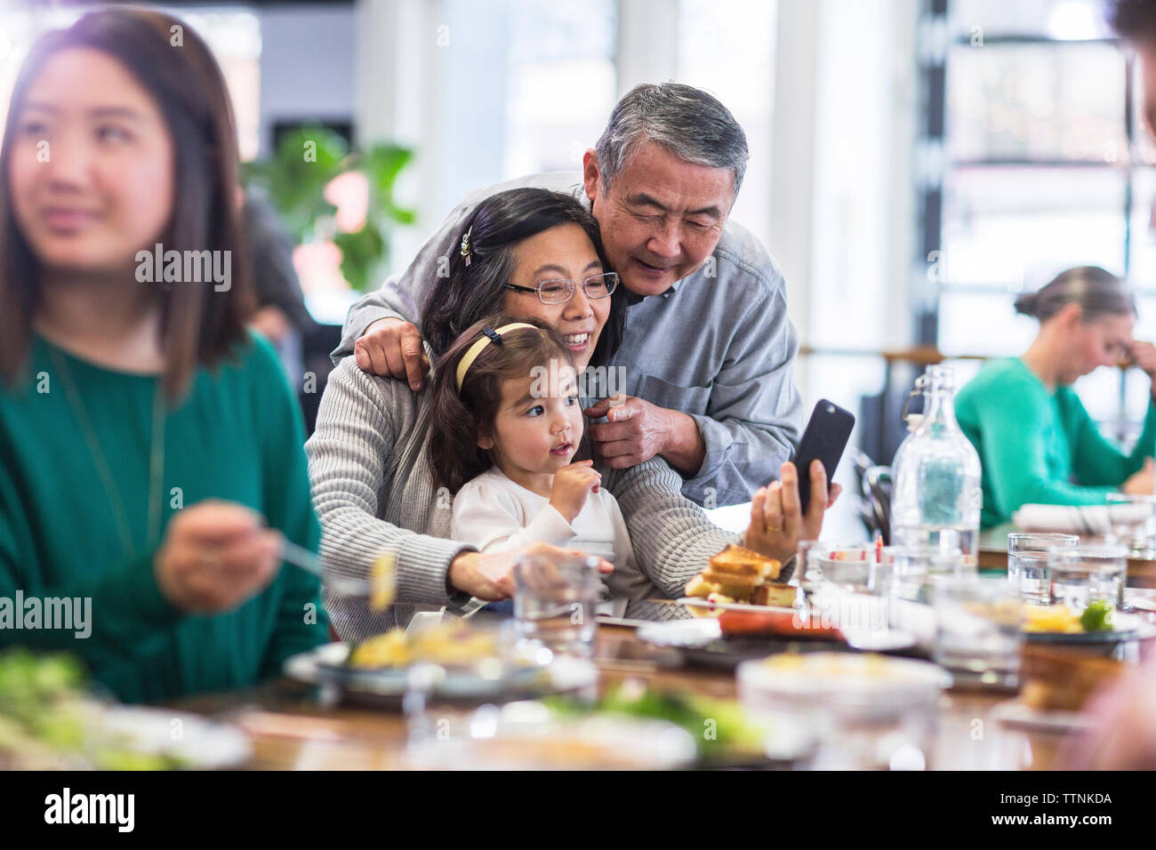 Grandparents taking selfie with granddaughter in restaurant Stock Photo