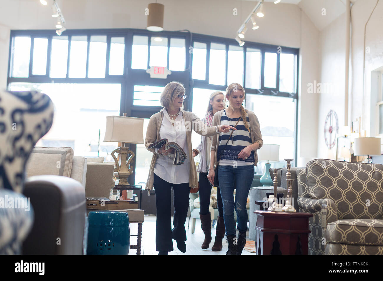 Saleswoman showing furniture to female customers in store Stock Photo