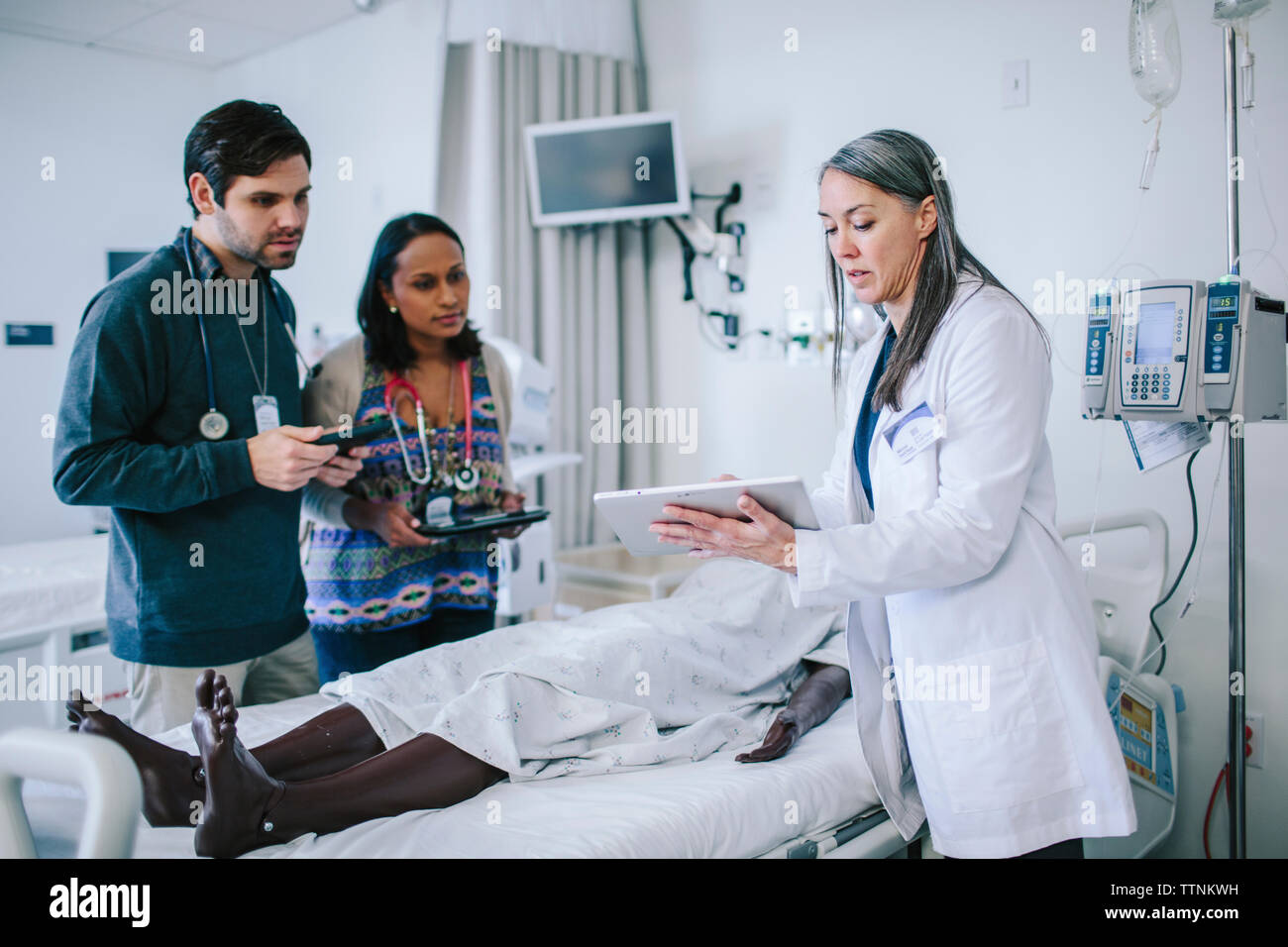 Female doctor training coworkers over tablet computer in medical school Stock Photo