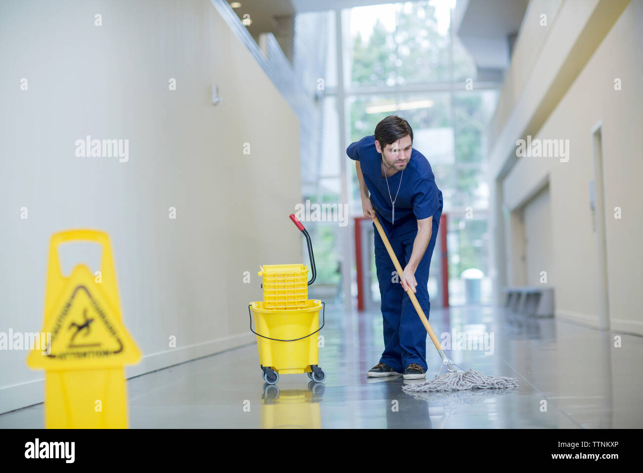 Male worker cleaning floor at hospital corridor Stock Photo