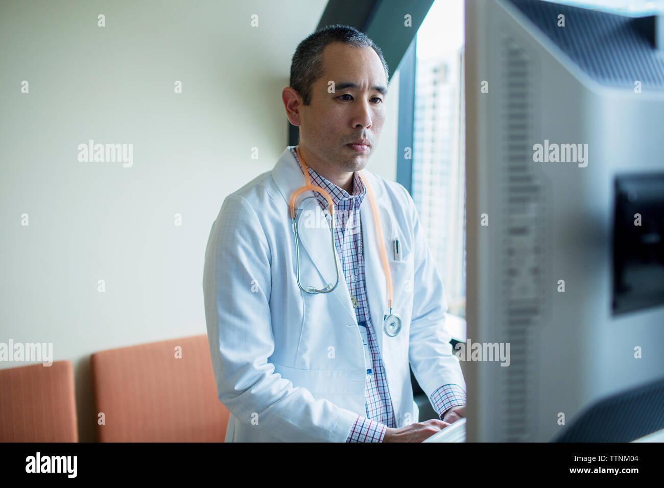 Confident male doctor using desktop computer in hospital ward Stock ...