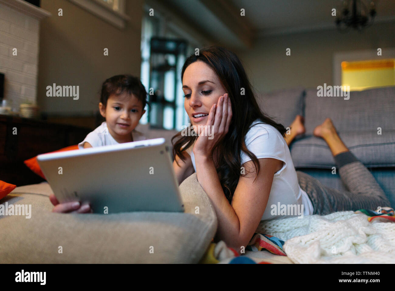 Girl looking at mother using tablet computer at home Stock Photo