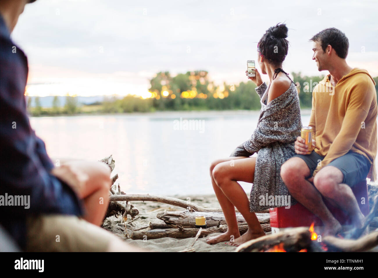 Friends at campfire against river Stock Photo