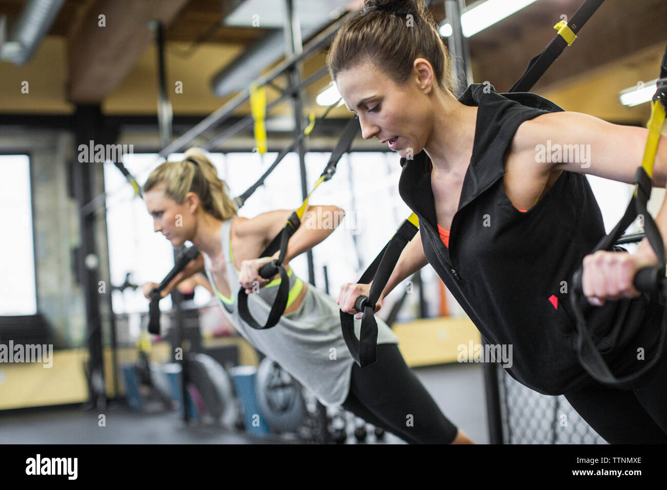 Instructor with woman exercising with resistance bands in gym Stock Photo