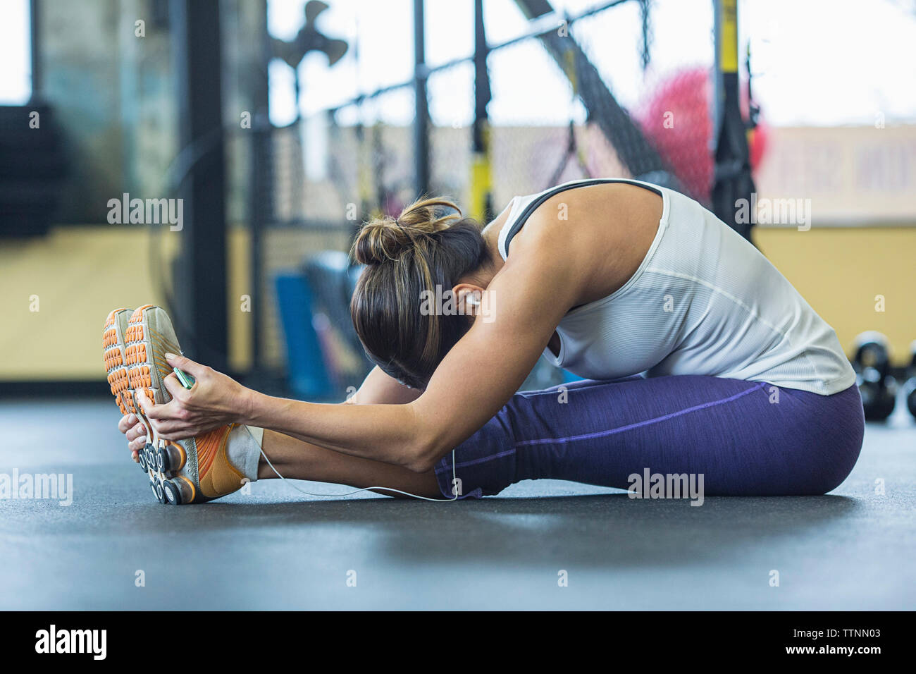 Woman practicing seated forward bend pose in gym Stock Photo