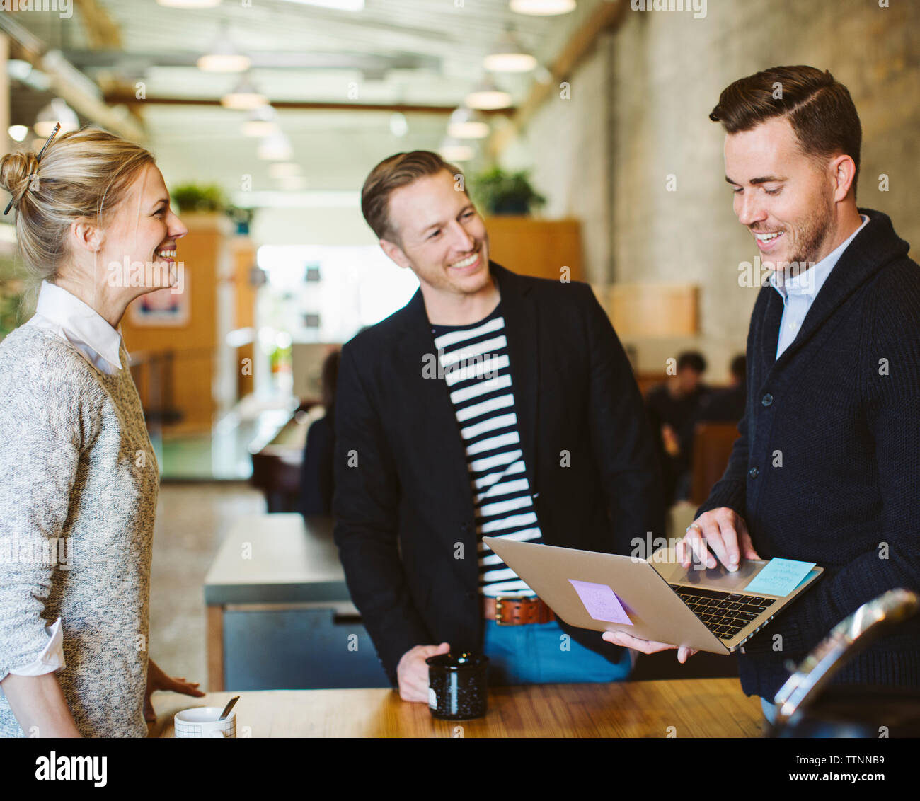 businessman using laptop computer while standing with colleagues in office Stock Photo