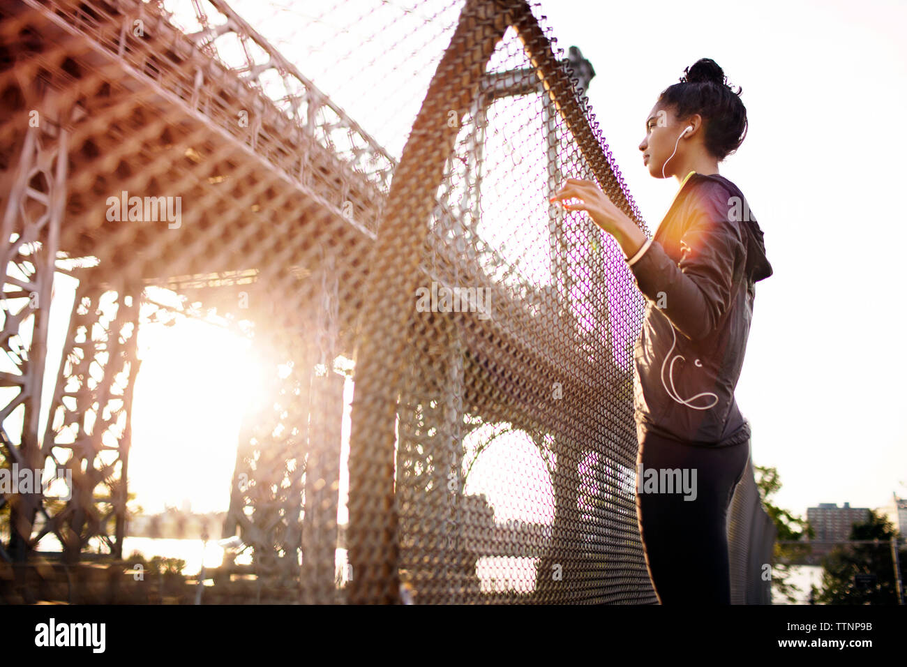 Young female jogger looking at Williamsburg Bridge on sunny day Stock Photo