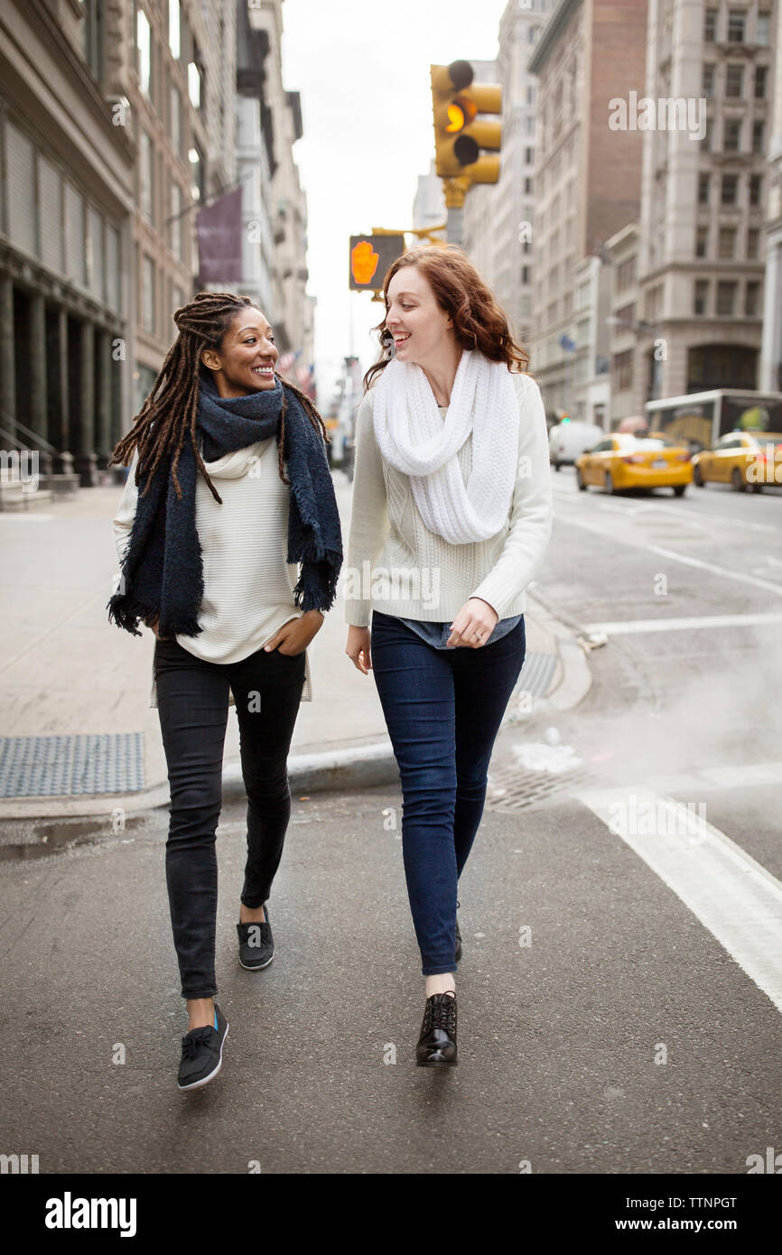 Cheerful women looking face to face while walking on street Stock Photo