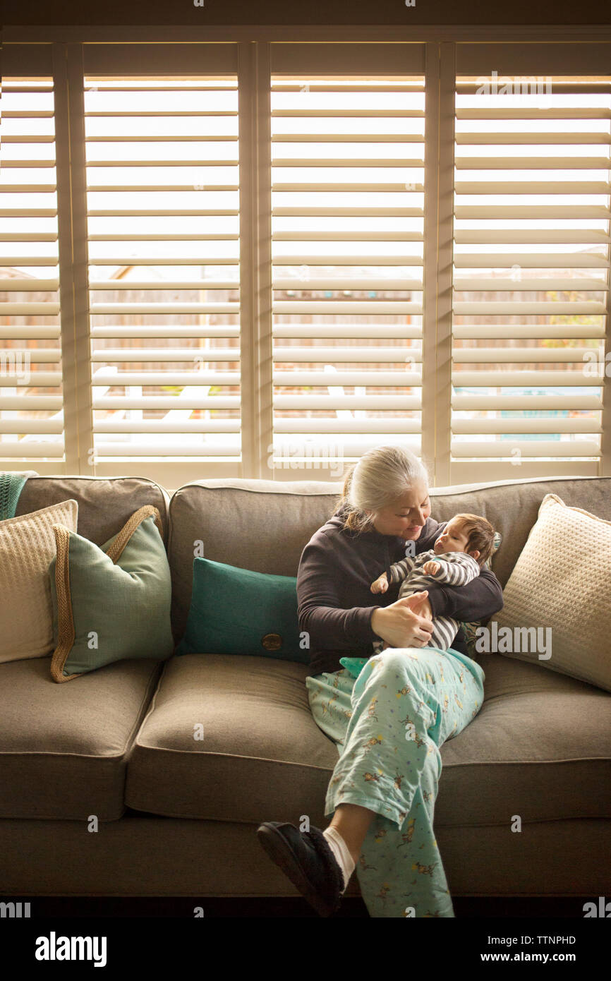 Grandmother playing with baby grandson on sofa at home Stock Photo