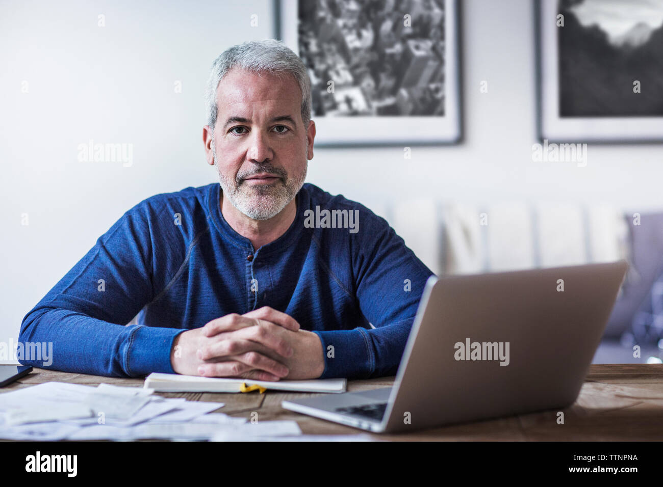 Portrait of confident mature man sitting at table in home Stock Photo