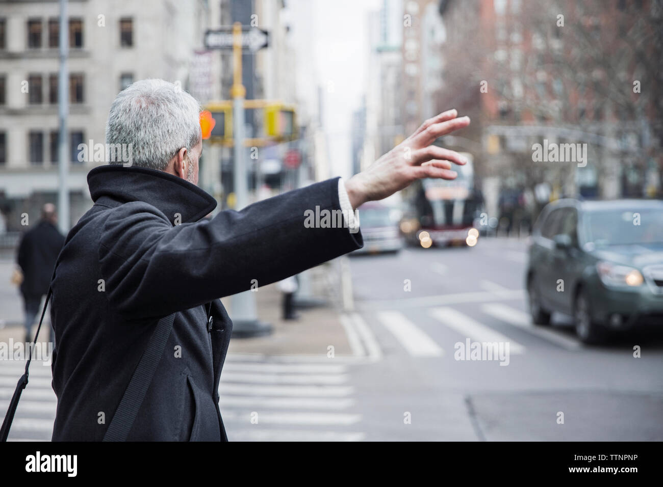 Side view of mature man hailing taxi on city street Stock Photo