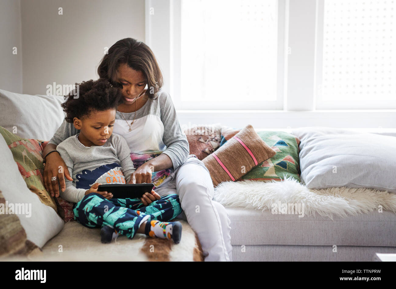 Mother and son using tablet computer on sofa at home Stock Photo