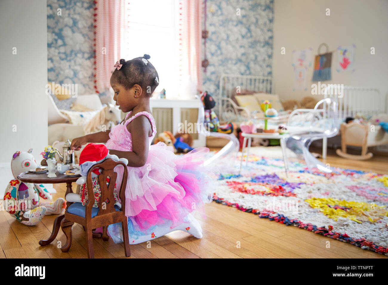 Side view of girl in pink dress having a tea party Stock Photo