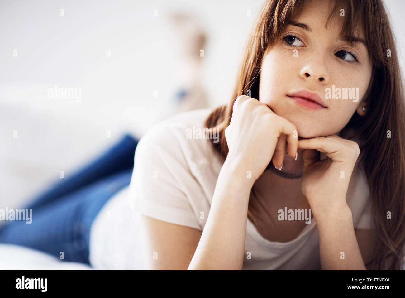 Thoughtful young woman lying on bed at home Stock Photo