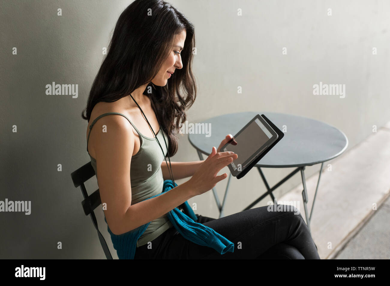 Young woman using tablet computer on chair outdoors Stock Photo