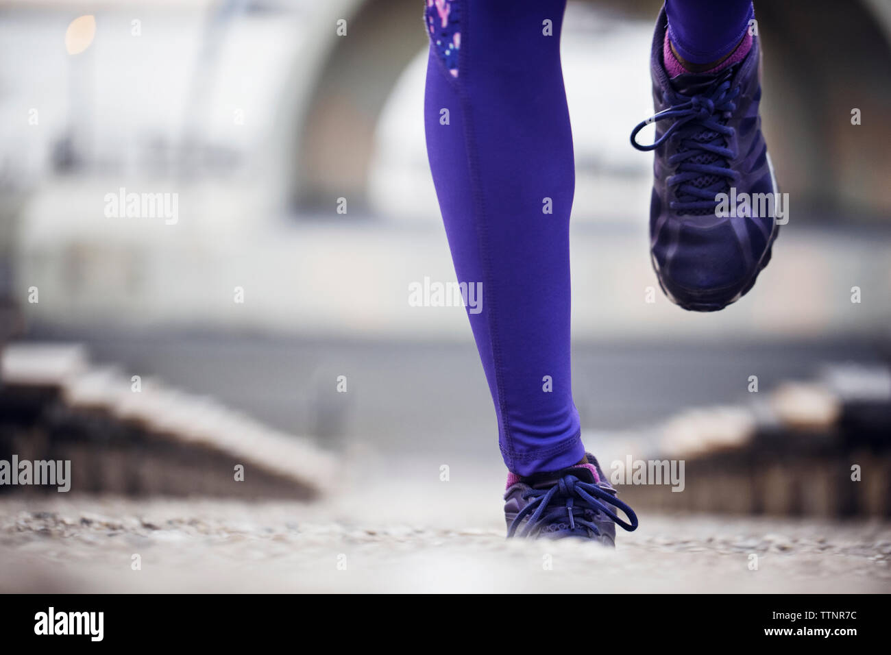 Low section of sporty woman running at stadium Stock Photo