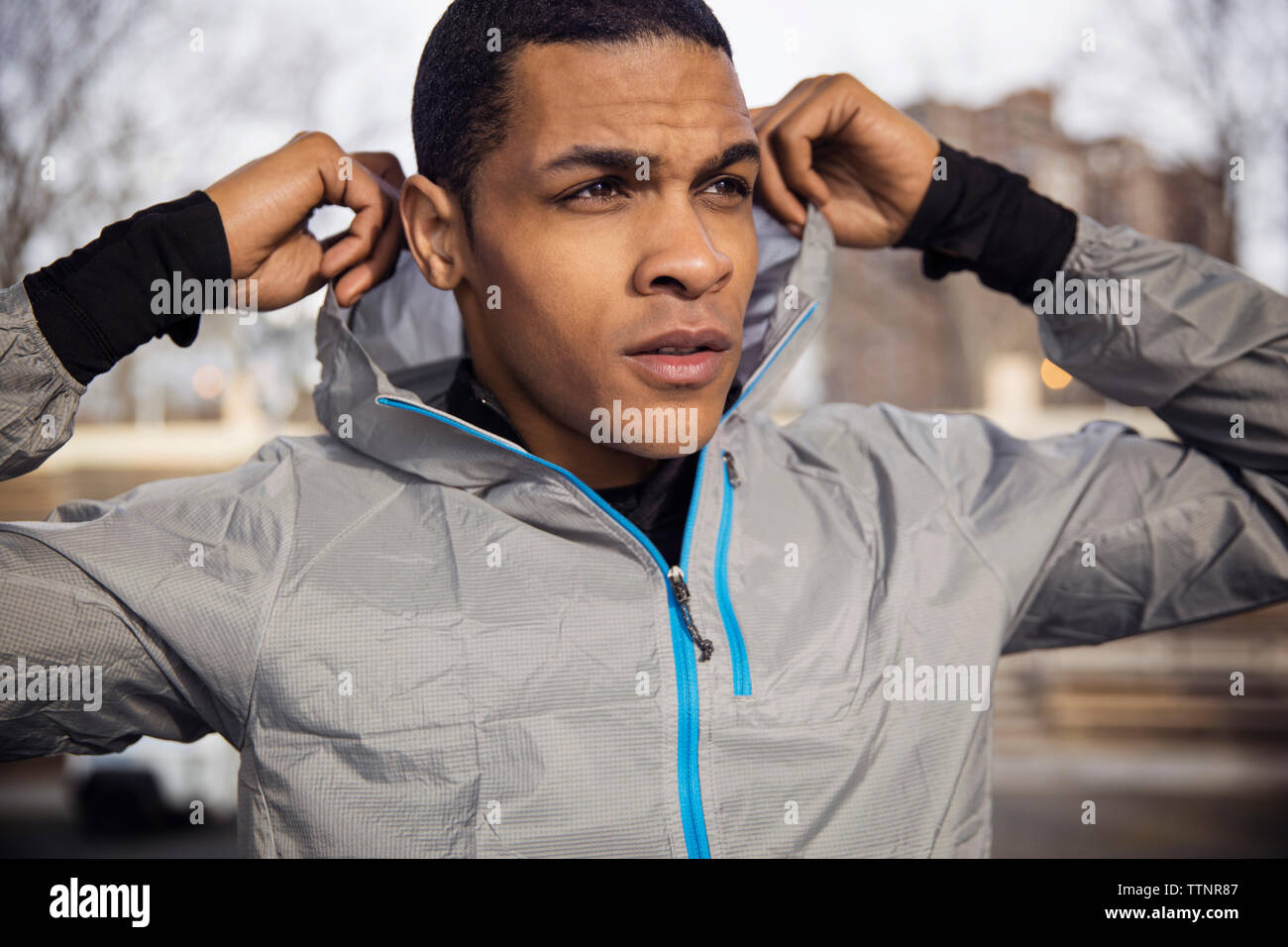 Confident male athlete wearing hooded jacket outdoors Stock Photo