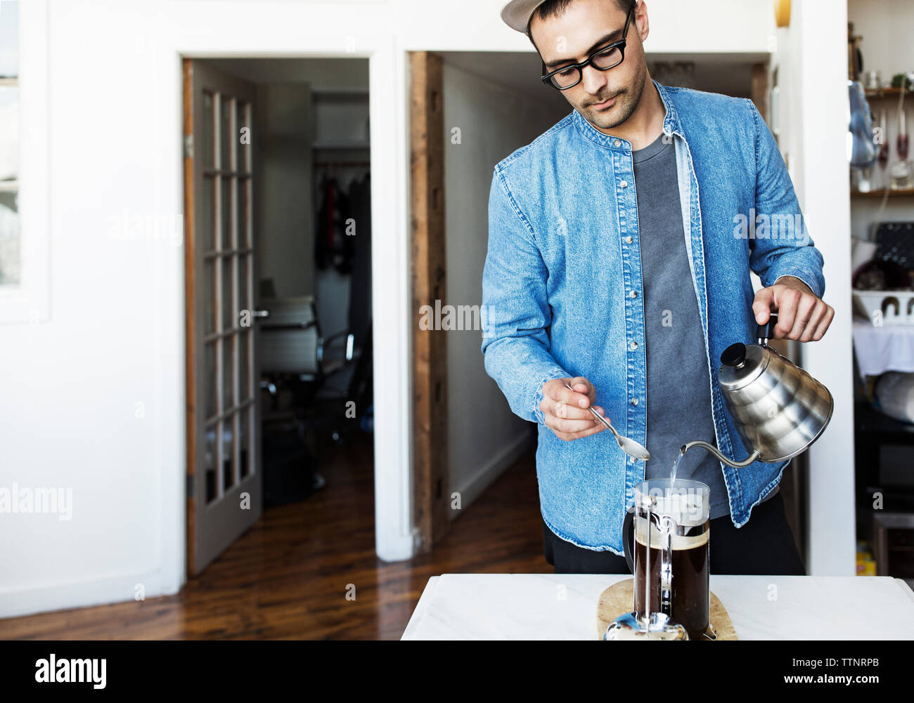 Man pouring boiling water in French press at home Stock Photo