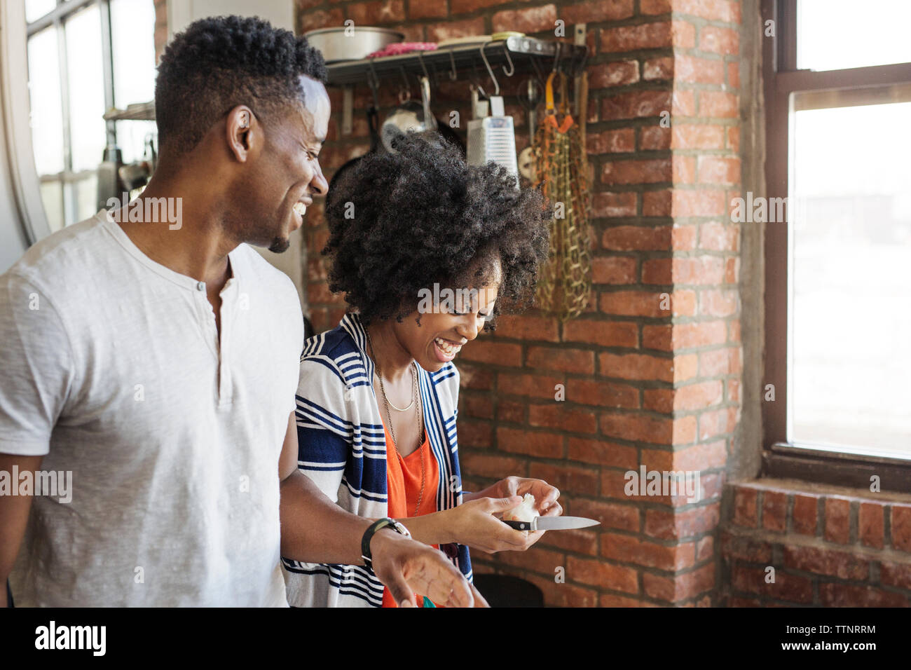 Happy man looking at girlfriend peeling garlic Stock Photo