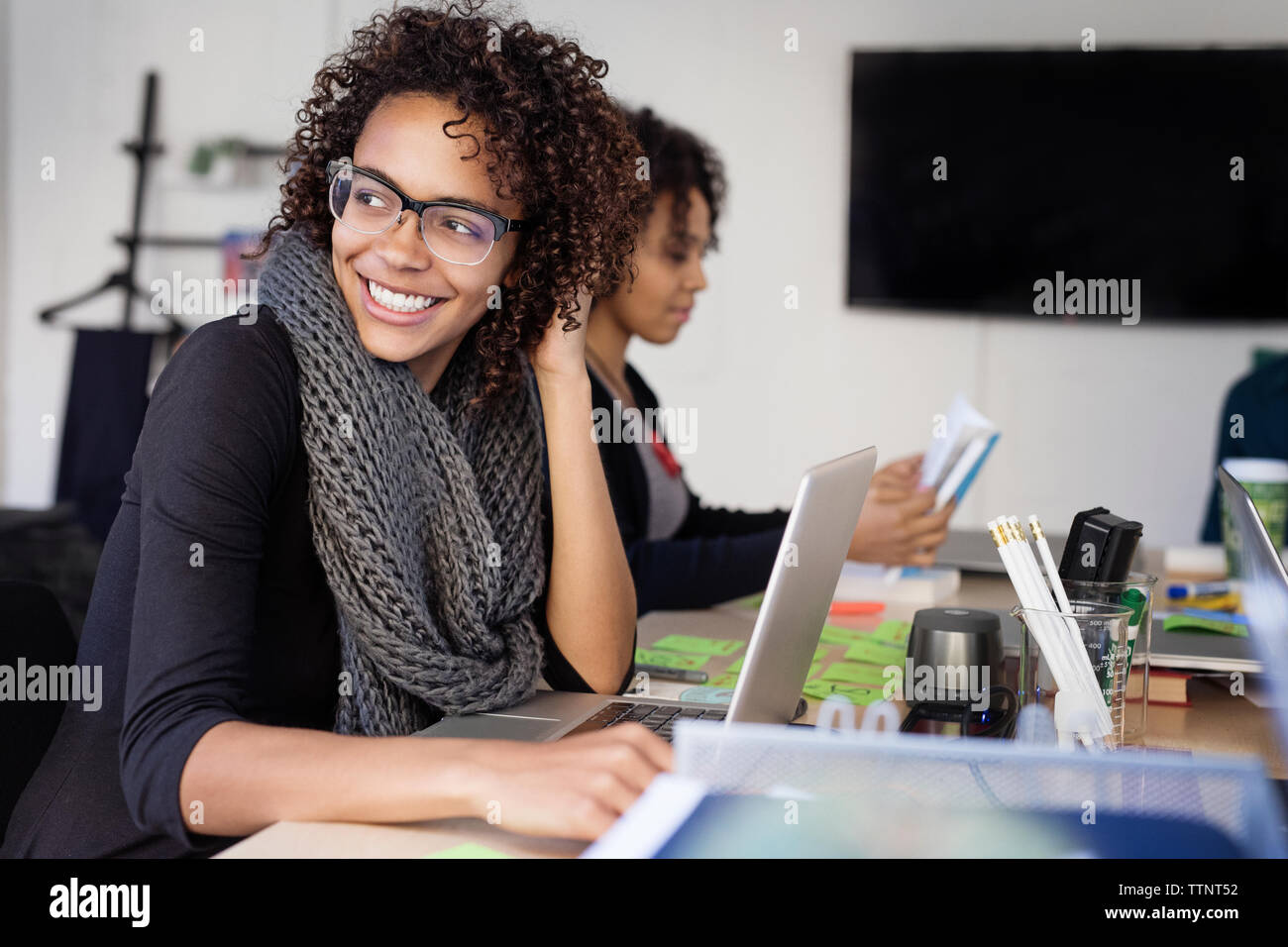 Smiling businesswomen with colleague at conference table in board room Stock Photo