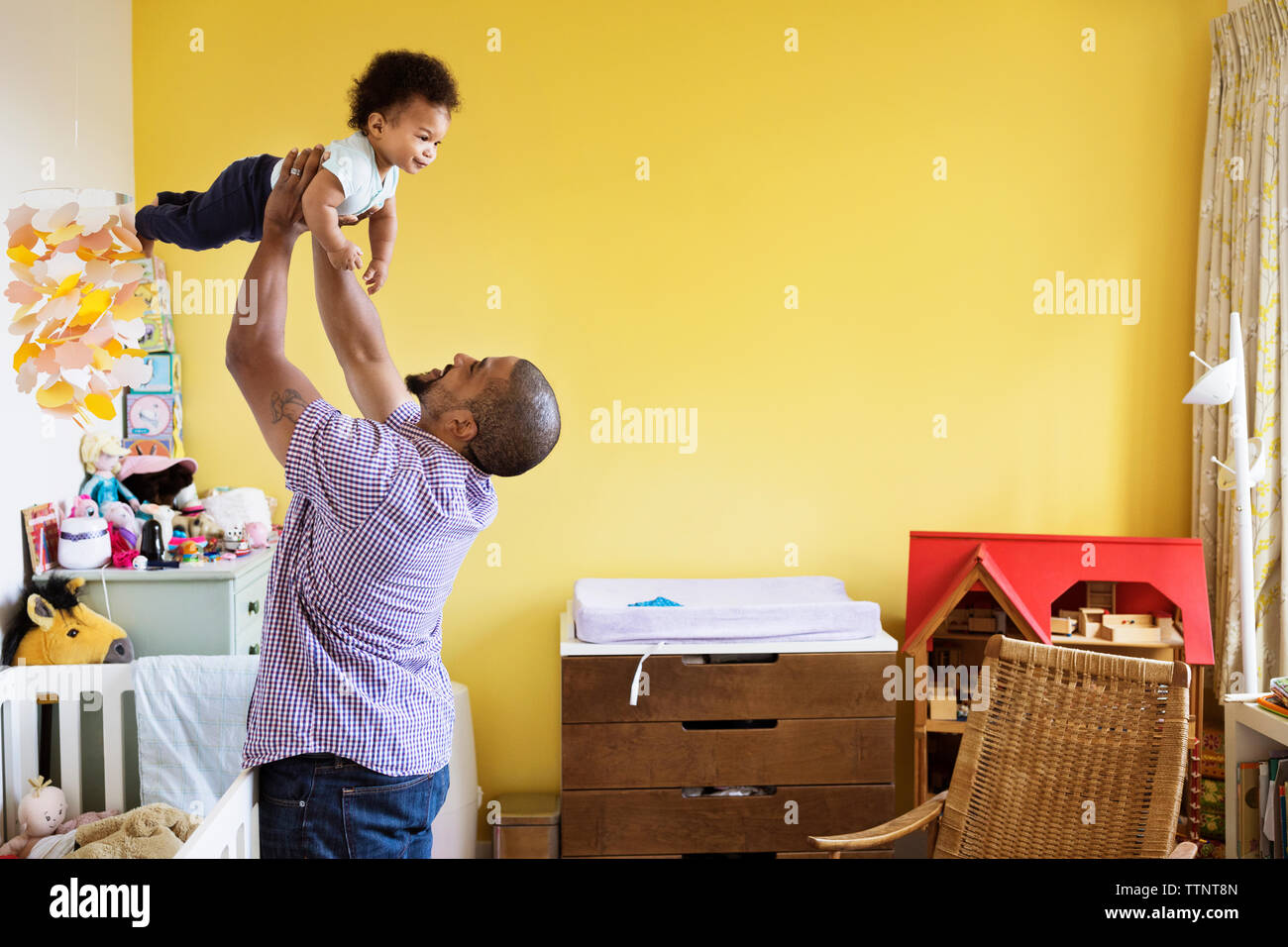 Happy man picking up son while standing at home Stock Photo