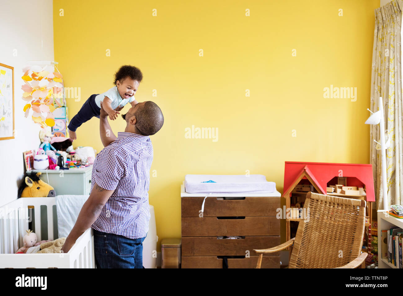 Playful man picking up son while standing at home Stock Photo