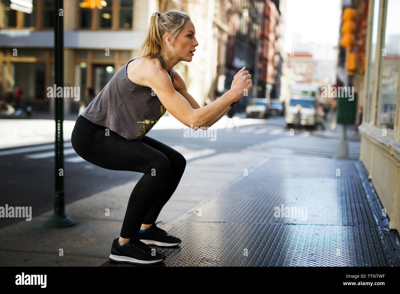 Confident athlete exercising at sidewalk in city Stock Photo