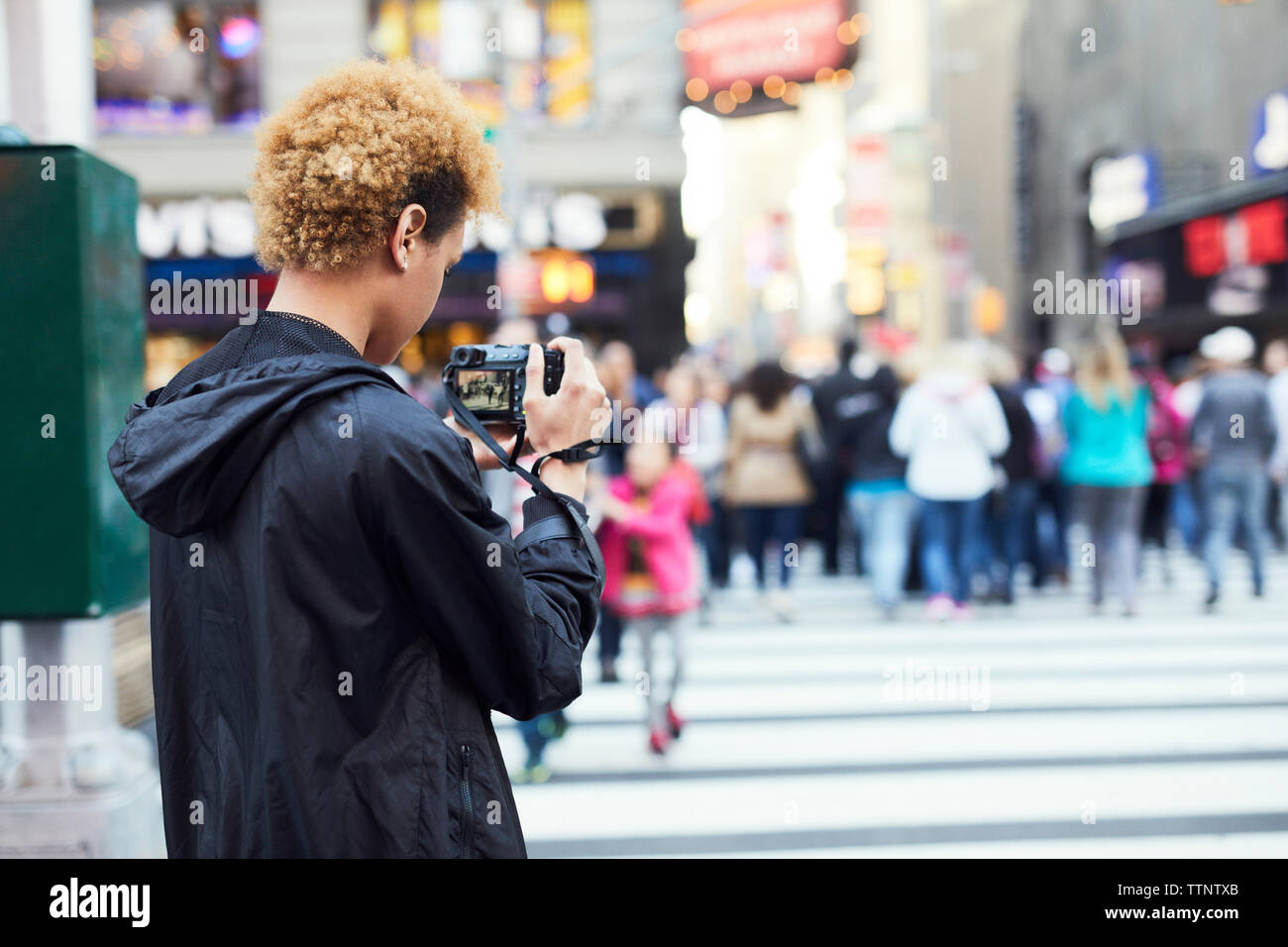 Rear view of young woman photographing on city street Stock Photo - Alamy