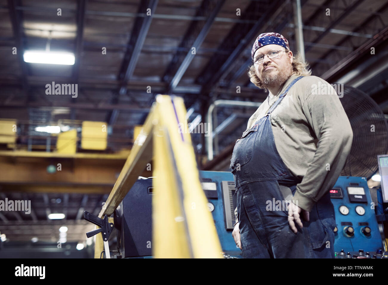 Low angle view of blue collar worker wearing bib overalls and headscarf while working in steel industry Stock Photo