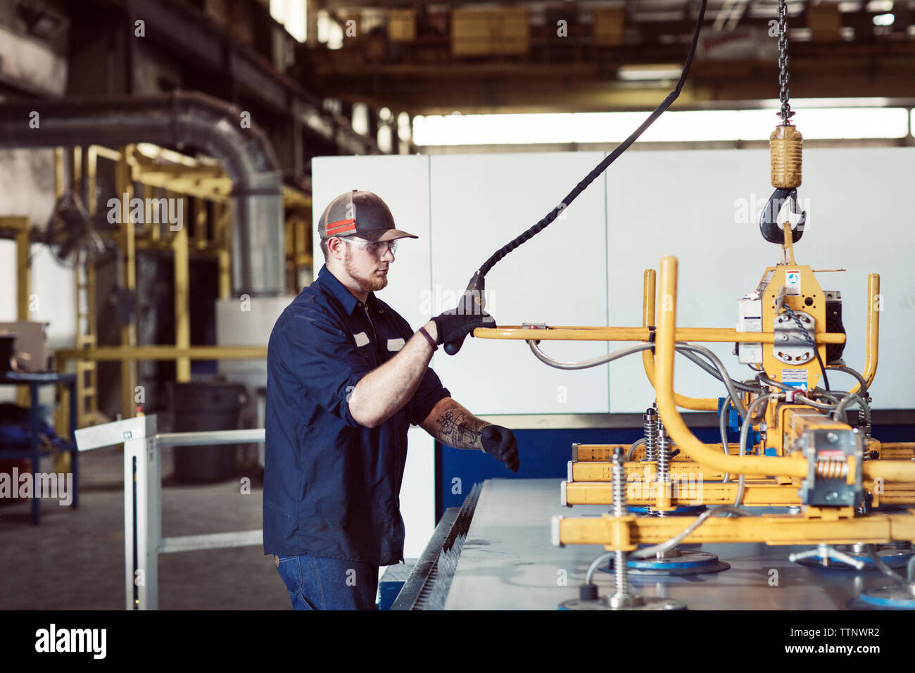 Side view of worker using machinery at industry Stock Photo - Alamy