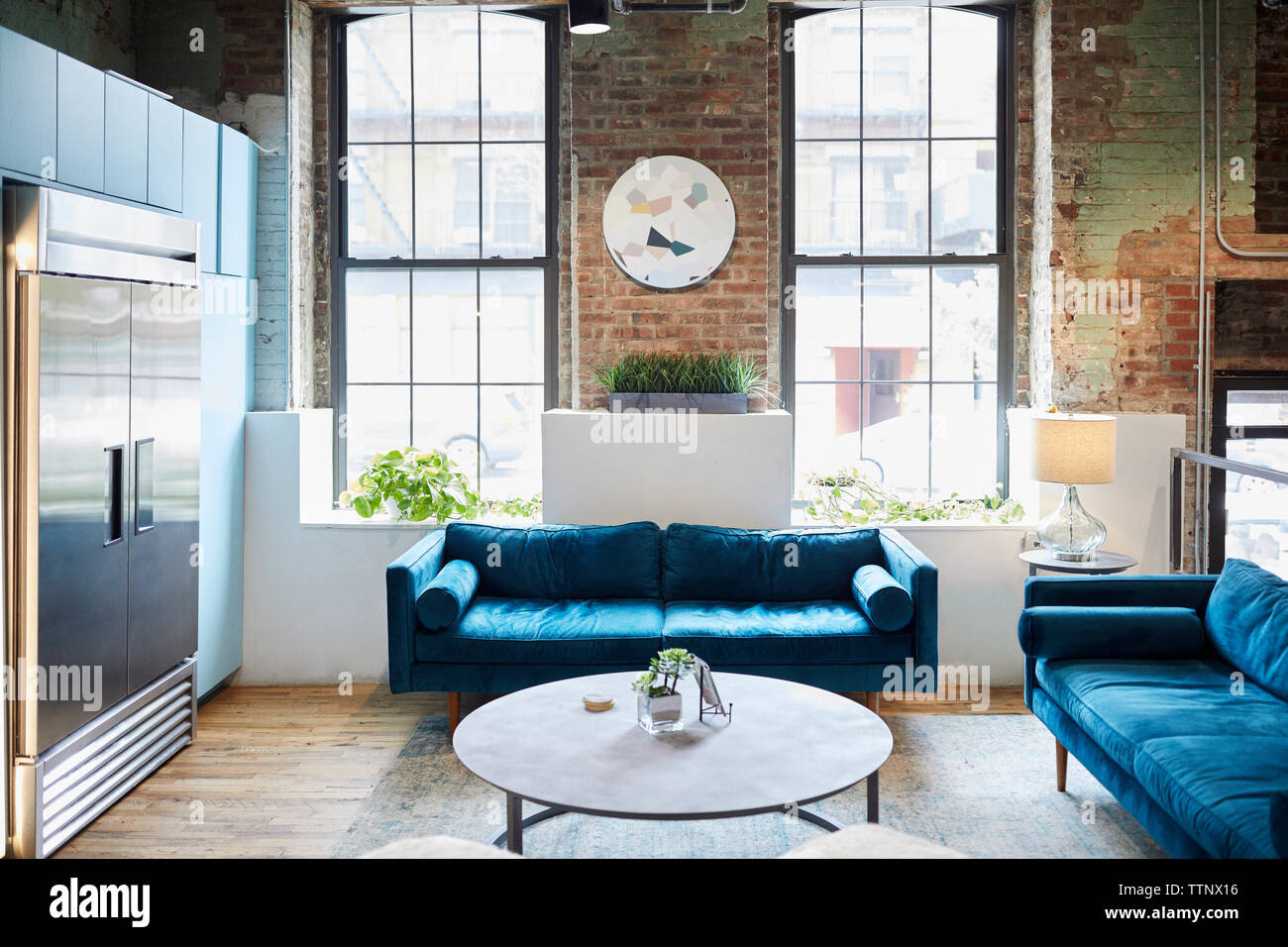 Blue sofas and coffee table against windows in creative office on sunny day Stock Photo