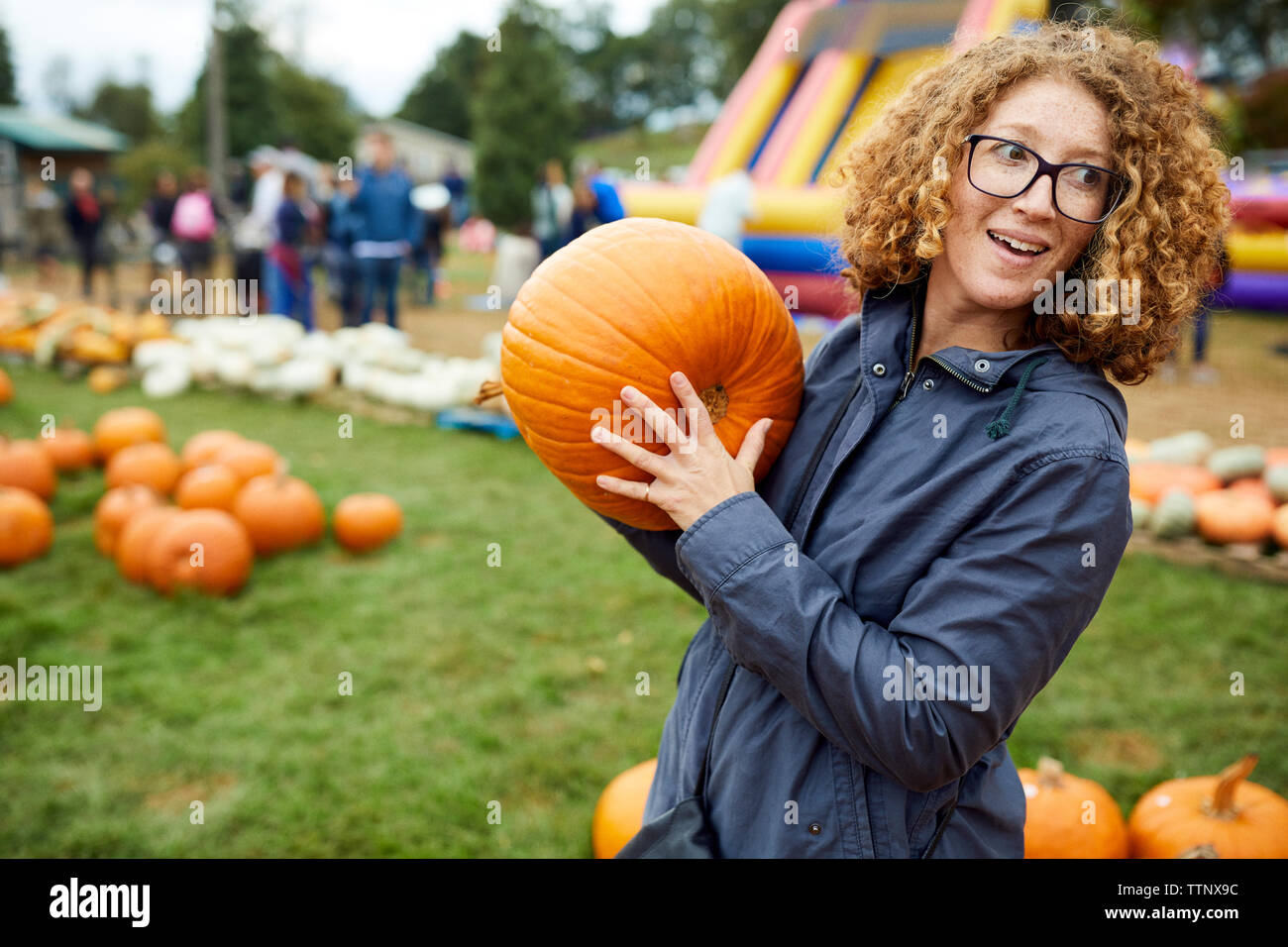 Woman holding pumpkin while standing at farm Stock Photo