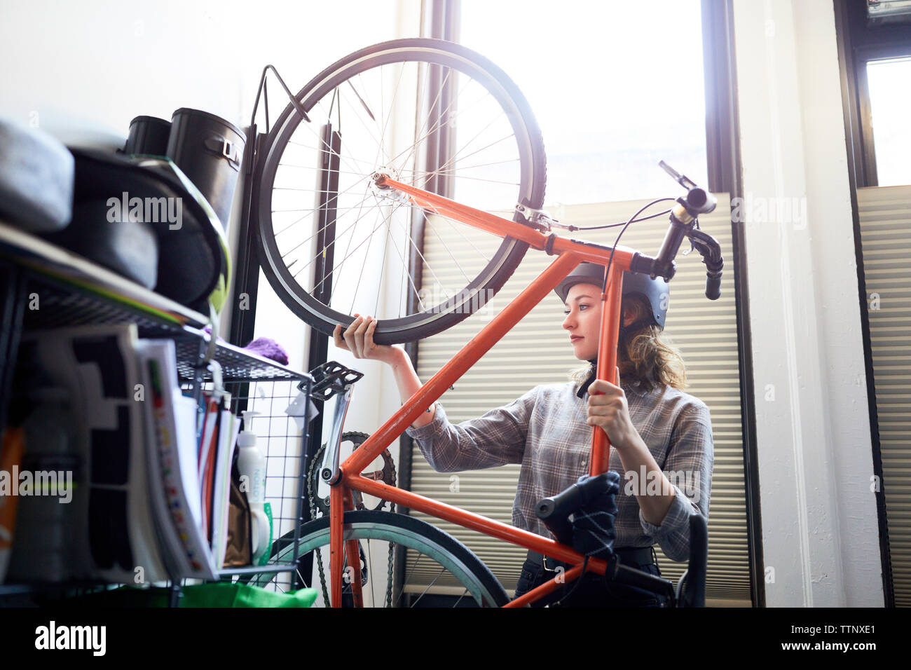 Businesswoman removing bicycle from rack in creative office Stock Photo